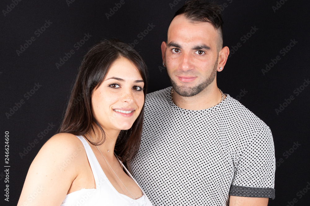 portrait of a young couple standing close together on black background portrait of a young couple standing close together on black background