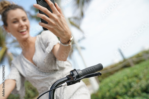 Gorgeous carefree young woman taking selfie on bicyle outdoors