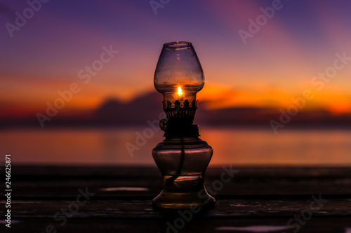 Beautiful old rustic oriental oil lamp silhouette in a beautiful amazing red velvet sunset sky at tropical island in Indian Ocean, Koh Phangan, popular tourist destination in Thailand.