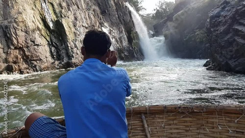 A boatman wearing blue shirt rowing a coracle in Cauvery river near waterfalls in Hogenakkal, Tamil Nadu, India photo