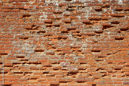 Very old weathered, damaged, badly repaired red brick wall close up full frame background