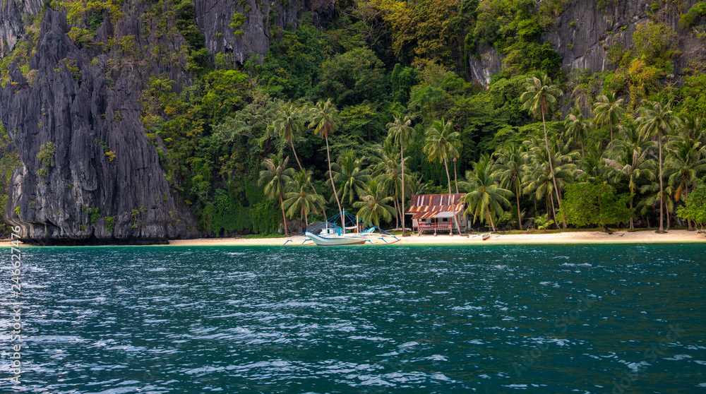 Beautiful landscape with beach and jungle. Rustic hut and traditional wooden boat of Philippines