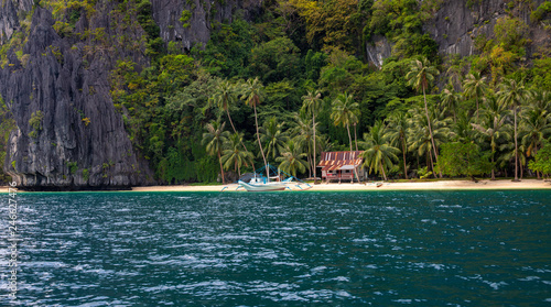 Beautiful landscape with beach and jungle. Rustic hut and traditional wooden boat of Philippines