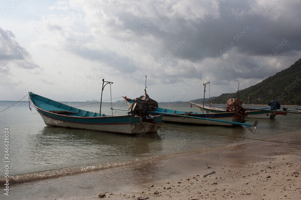 Long-tail boats under cloudy sky in harbor of Koh Phangan island, Thailand