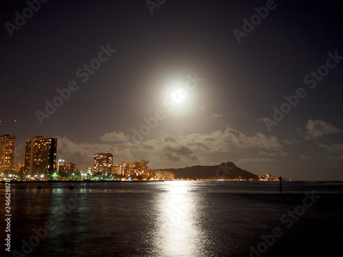 Full Large Moon hangs over Diamond Head Crater, Waikiki hotels, and Marina at Night