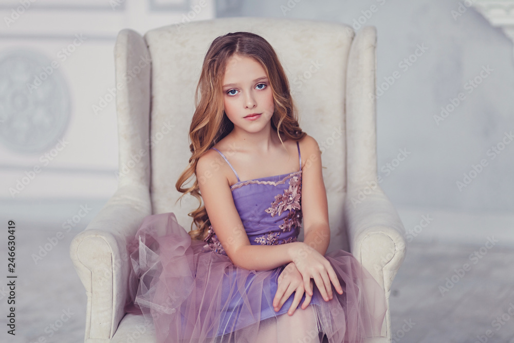 Fototapeta premium portrait of beautiful caucasian little girl wearing dress, sitting on chair