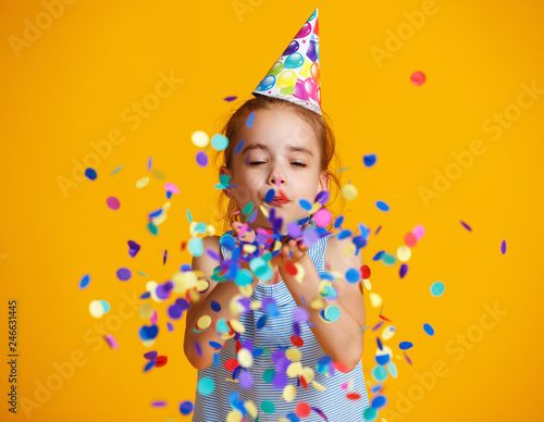 happy birthday child girl with confetti on yellow background.