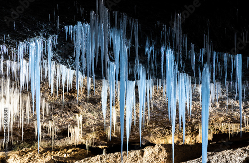 Many icicles hanging from the ceiling of the cave. photo