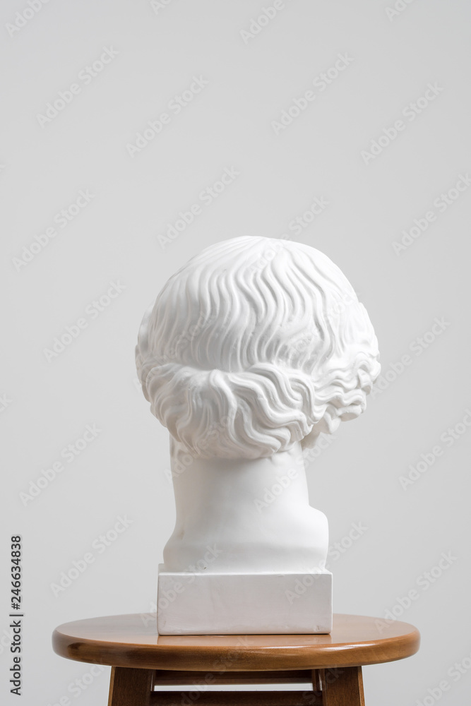 Plaster head, antique sculpture for learning to draw. Standing on a stool on a white background. Plaster head, antique sculpture for learning to draw. Standing on a stool on a white background.