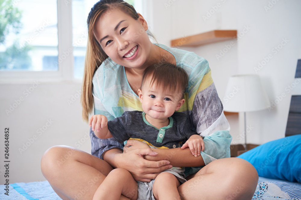 Portrait of young mother and her happy kid sitting on sofa Portrait of young mother and her happy kid sitting on sofa
