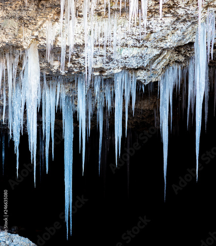 Many icicles hanging from the ceiling of the cave. photo