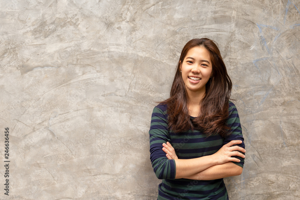 Young pretty asian woman smiling in grey concrete wall background.