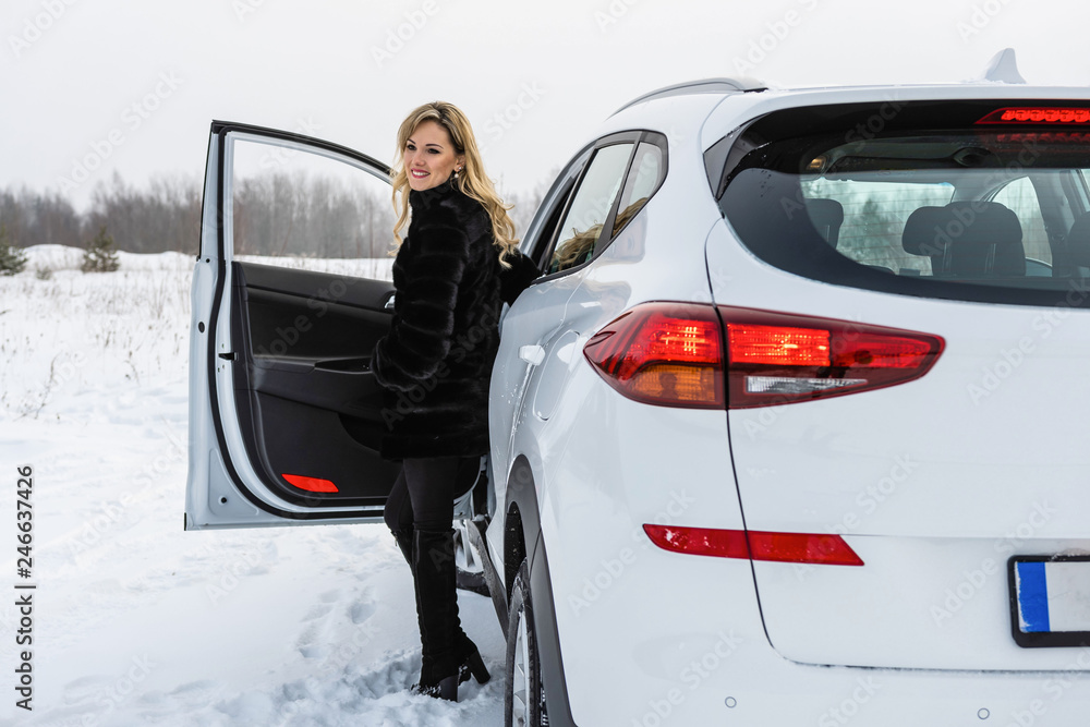 The blonde woman gets out of the white suv car and looks back. The blonde woman gets out of the white suv car and looks back.