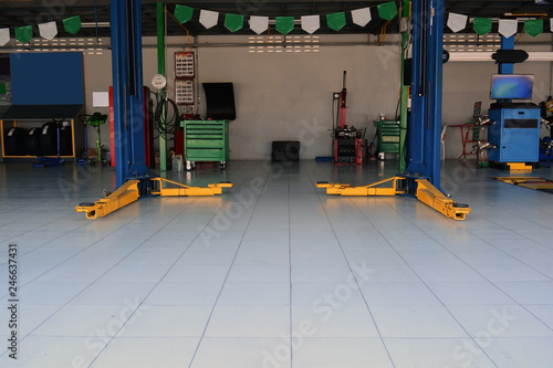 the yellow lift  hand at the bottom of  the lift post and other  accessory machine  at the car repair shop