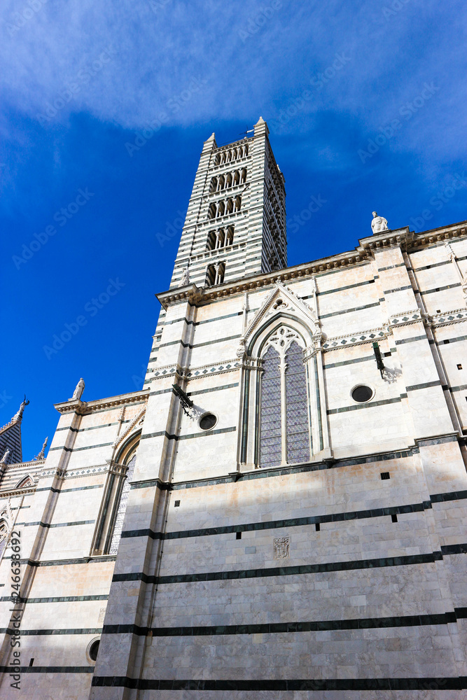 Siena cathedral bell tower, made from white marble on the blue winter sky background, Tuscany, Italy