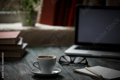 A cup of coffee in the workplace on a wooden table.