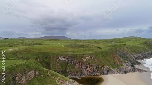 Aerial tracking forward above a beach to reveal Faraid head and Balnakeil beach in northern Scotland. photo