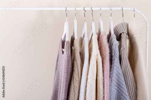 Warm knitted clothes hanging on a rack