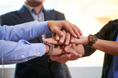 Business people stacking hands to express unity, trust and teamwork