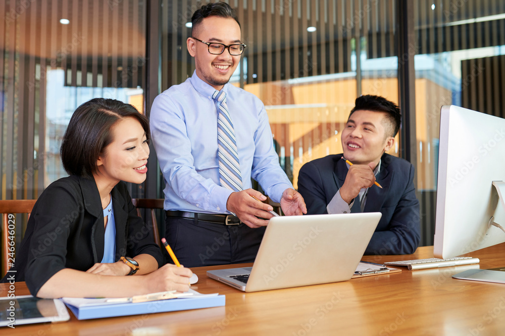 © DragonImages - Smiling Asian businessman presenting his idea to coworkers at meeting © DragonImages - Smiling Asian businessman presenting his idea to coworkers at meeting