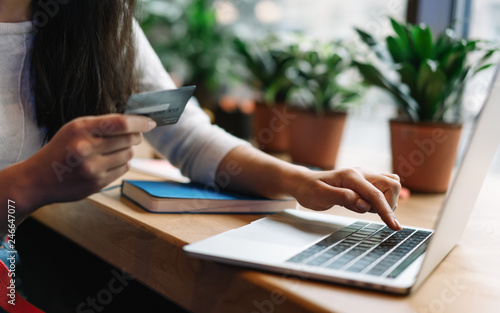 Close up woman s hand holding credit card using laptop computer for online shopping with cash back  discount sales  low prices. Online store concept. Female planning travel and booking tickets