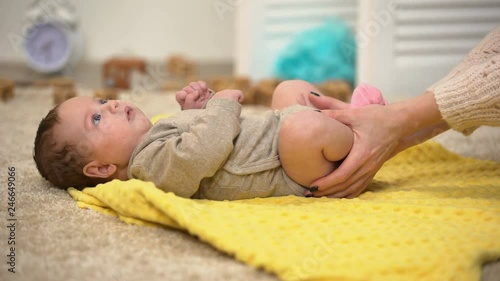 Lady massaging baby legs, thigh joints dysplasia prevention, reducing colic pain photo