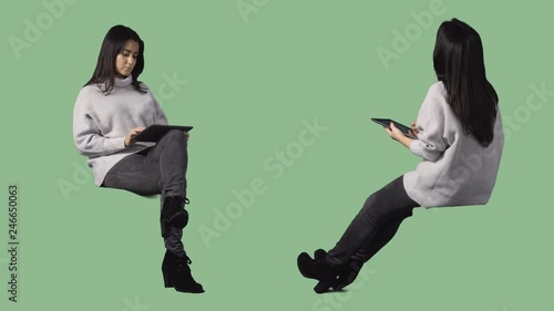 Brunett woman is sitting and reading tablet computer. Cut out on alpha background