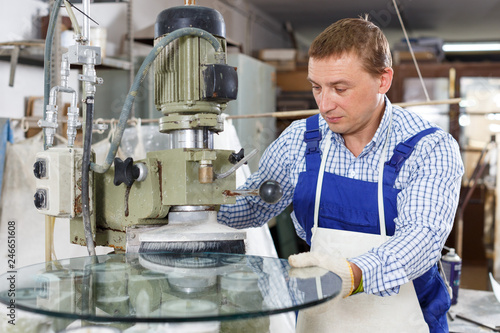 Bilde på lerret Male glazier with female assistant working on curved glass beveling machine