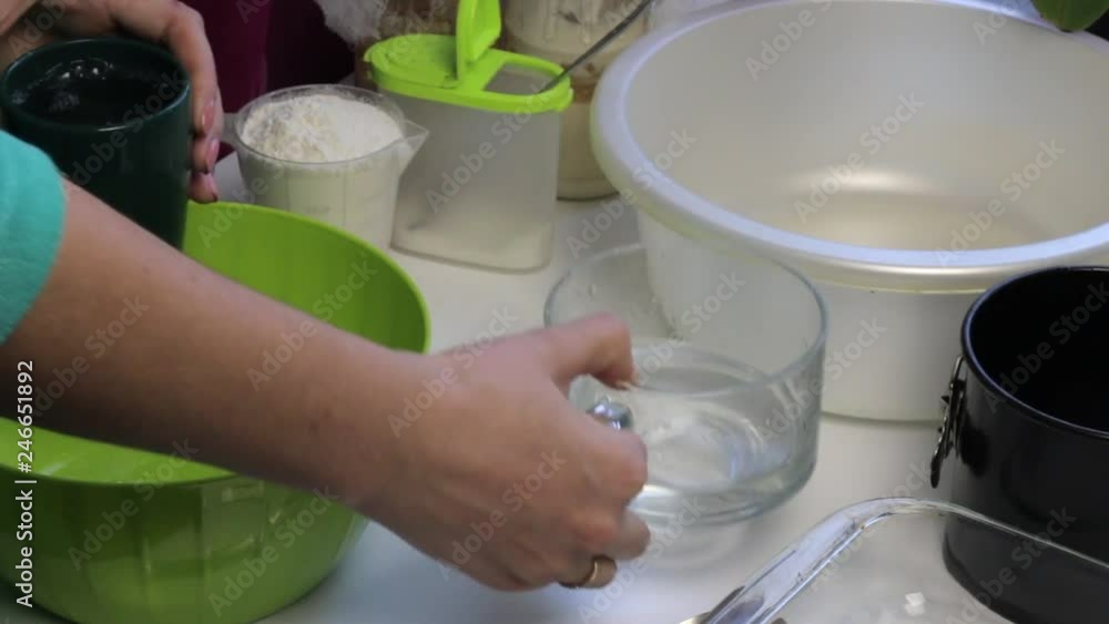 A woman pours water into a basin for the subsequent kneading of dough. Cooking bread at home. A woman pours water into a basin for the subsequent kneading of dough. Cooking bread at home.