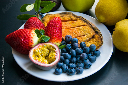 Vegan breakfast: variety of fruits, nuts and berries on the grey wooden table, selective focus; fruit salad