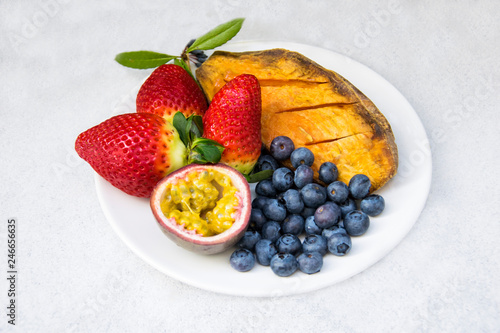 Vegan breakfast: variety of fruits, nuts and berries on the grey wooden table, selective focus; fruit salad