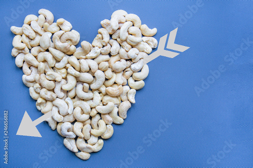 Cashew nuts shaped as a heart on a blue background. top view.