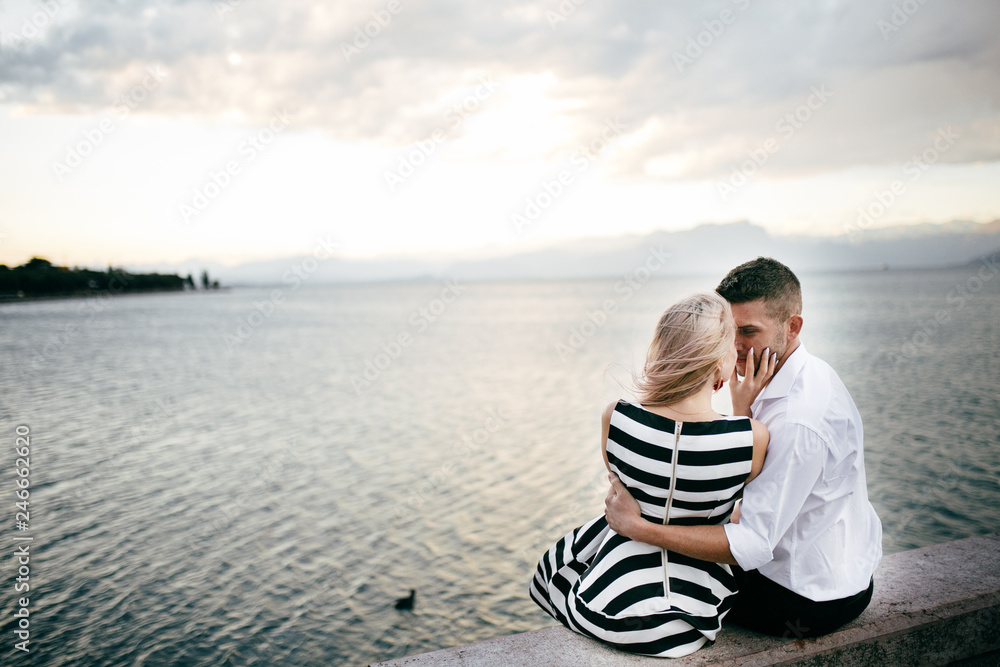 Portrait of an attractive young man looking his pretty woman on nature near the lake