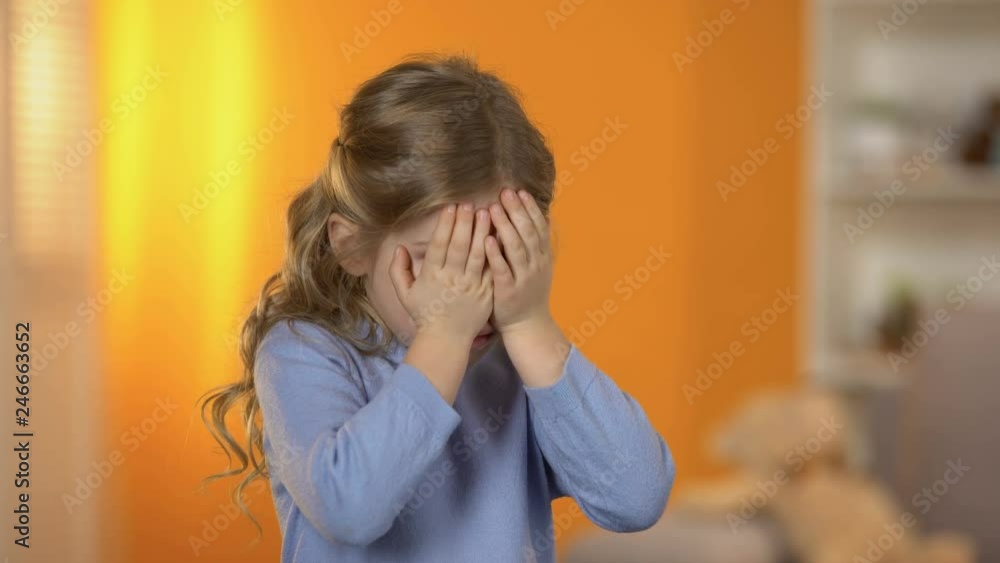 Pretty preschool girl closing eyes with hands, suffering bullying, no friends Pretty preschool girl closing eyes with hands, suffering bullying, no friends