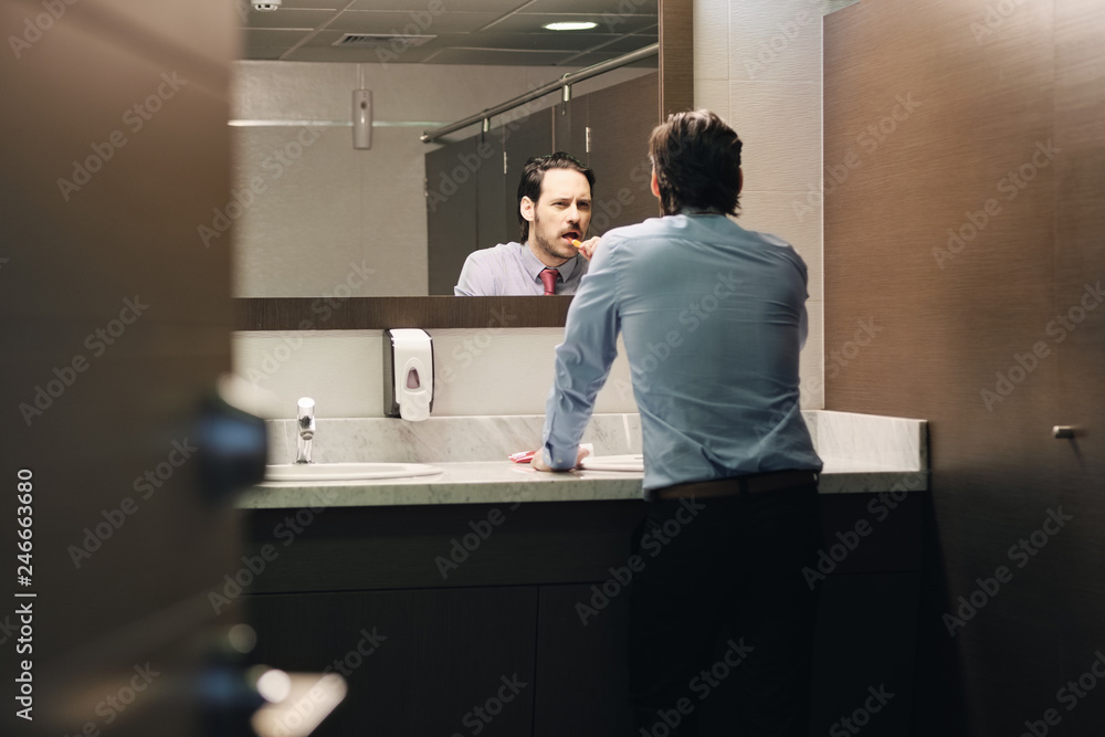Business Man Brushing Teeth After Lunch Break In Office Bathroom Business Man Brushing Teeth After Lunch Break In Office Bathroom