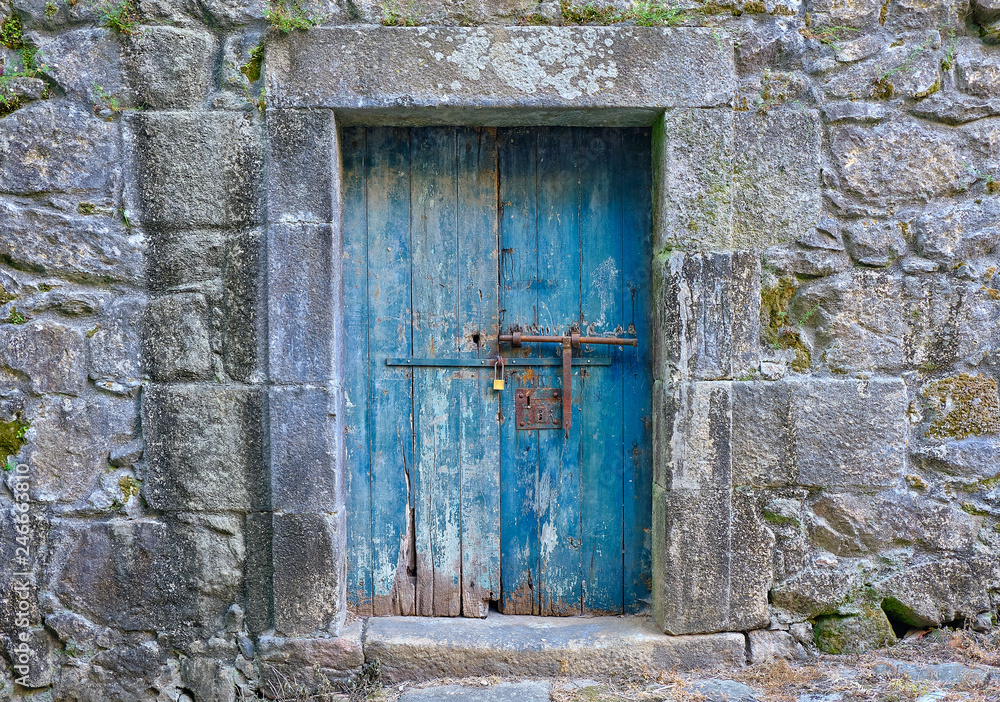 Rustic old blue wooden door, locked, showing aging and wear and tear on old stone building Rustic old blue wooden door, locked, showing aging and wear and tear on old stone building