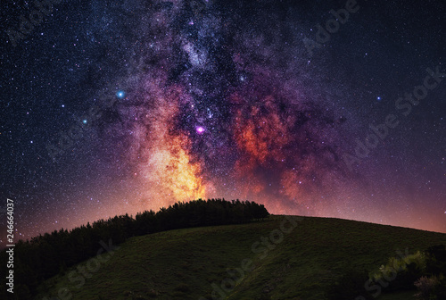 Close up milky way galaxy and mountain with trees on the top.