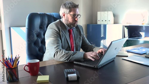 Tired director snorting bored and working non stop. Annoyed caucasian manager typing on keyboard, stressed chief writing on computer dullness. Busy man at office, no break time, stressful lifestyle