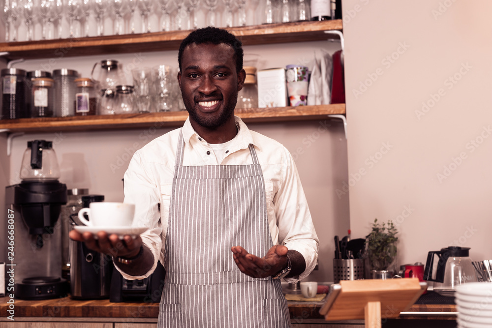 Pleasant good looking man showing you his coffee Pleasant good looking man showing you his coffee