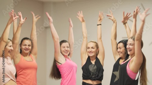 Slim girls working out in the gym and putting hands on hands together creating circle like cheerleaders after training. They are positive, smiling, laughing, inspiring. Teamwork concept photo