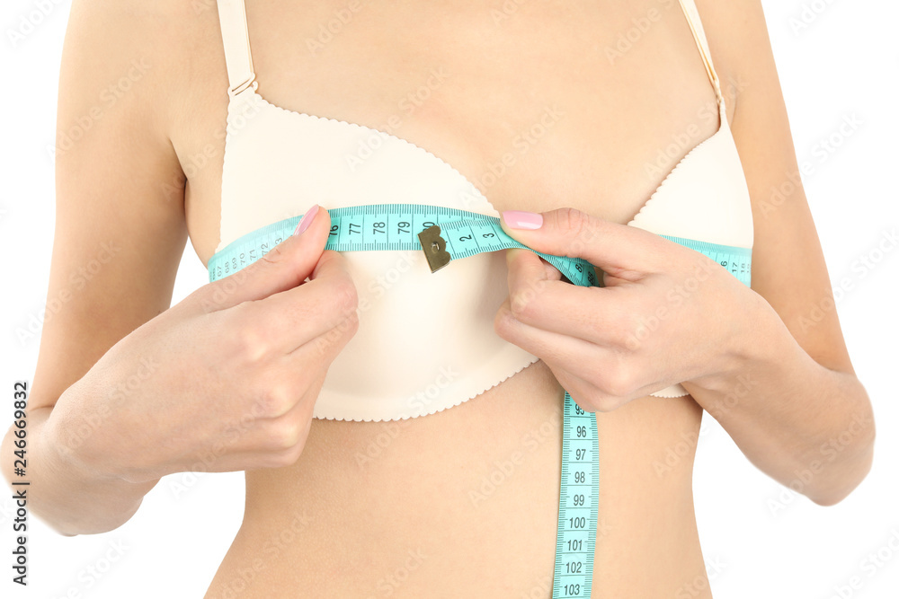 Young woman measuring breast size on white background, closeup