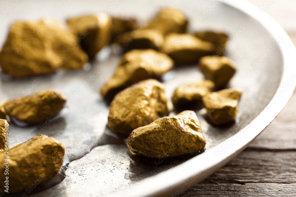 Plate with gold nuggets and water on table, closeup Plate with gold nuggets and water on table, closeup