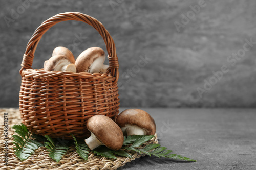 Wicker basket of fresh champignon mushrooms on table, space for text