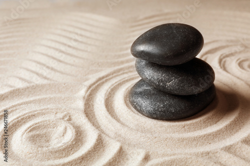 Stacked zen garden stones on sand with pattern, space for text. Meditation and harmony