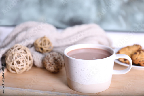 Cup of aromatic cacao on wooden tray near window, closeup