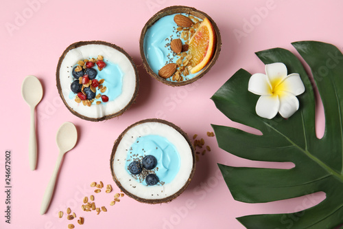 Flat lay composition with yummy spirulina smoothie in coconuts on color background
