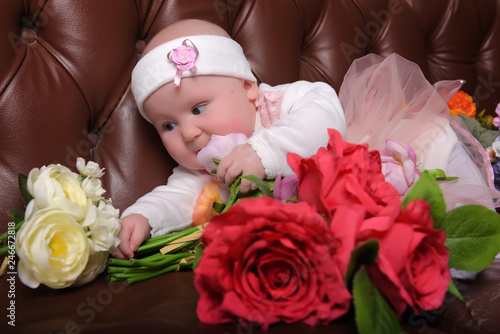 girl five months in a pink dress with bouquets of flowers photo