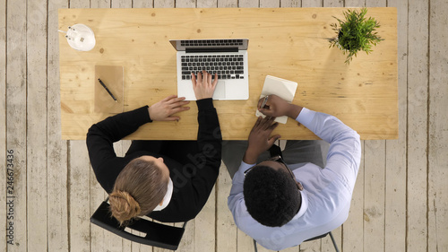 Two entrepreneurs sitting together working in an office desk putting notes to notebook