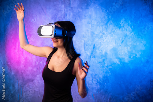 Beautiful Pro Gamer Girl Wearing Virtual Reality Headset Plays in Online Video Game, Gesturing. Cool Retro Neon Colors in the Room © romankosolapov