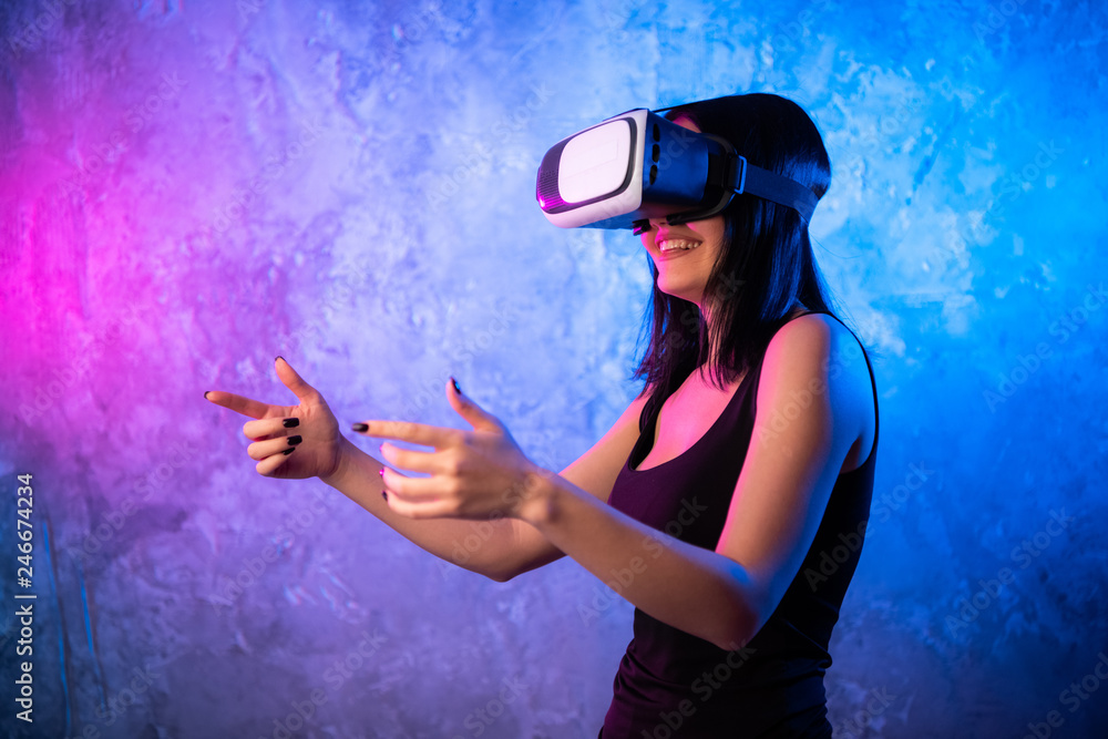 Wondering Young Woman in Virtual Reality Glasses neon colored background. Shocked Girl wearing VR device. Close-up of Female with VR headset. Stock Photo | Adobe Stock